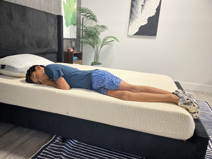 A young boy lying in the side-sleeping position on the 5 Little Monkeys mattress.