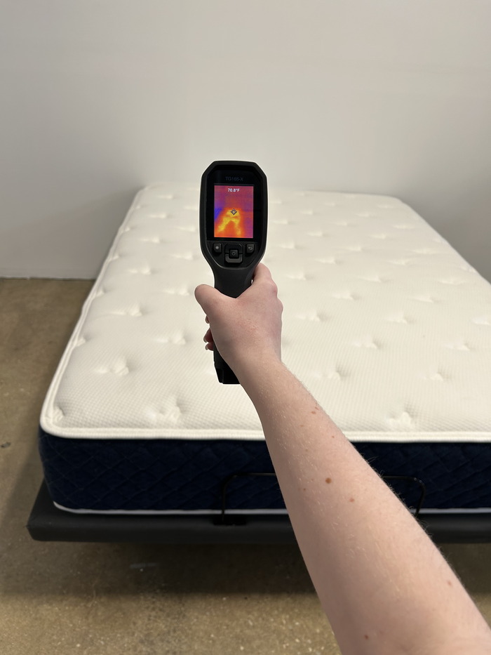 A closeup of someone aiming a thermal gun at the Brooklyn Bedding Signature Hybrid mattress in order to get its temperature.