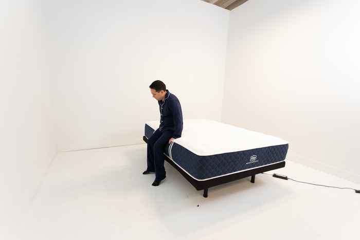 A man sitting on the edge of the Brooklyn Bedding Signature Hybrid mattress.