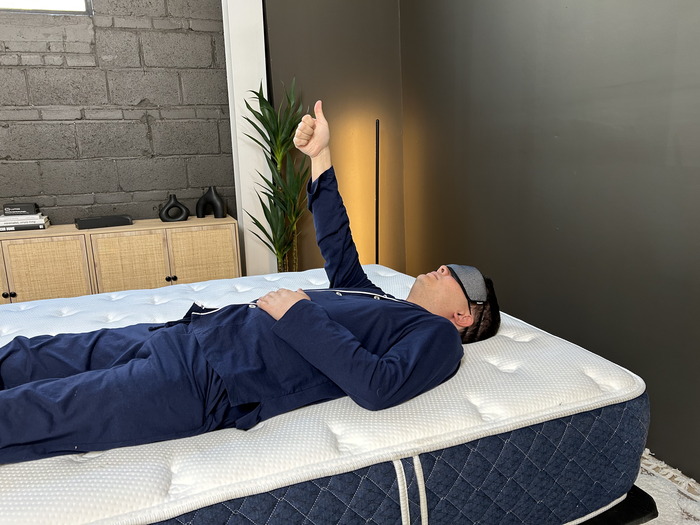 A man lying on the Brooklyn Bedding Signature Hybrid mattress and giving a thumbs up to indicate whenever he feels movement.