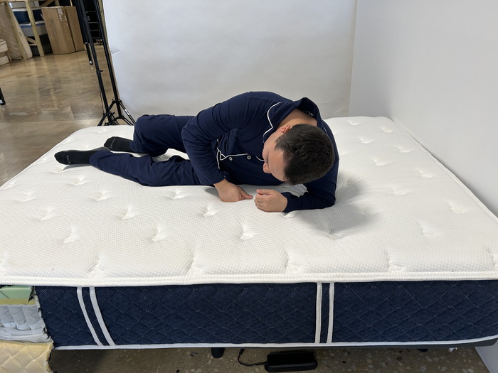 A man switching sleeping positions on top of the Brooklyn Bedding Signature Hybrid mattress.