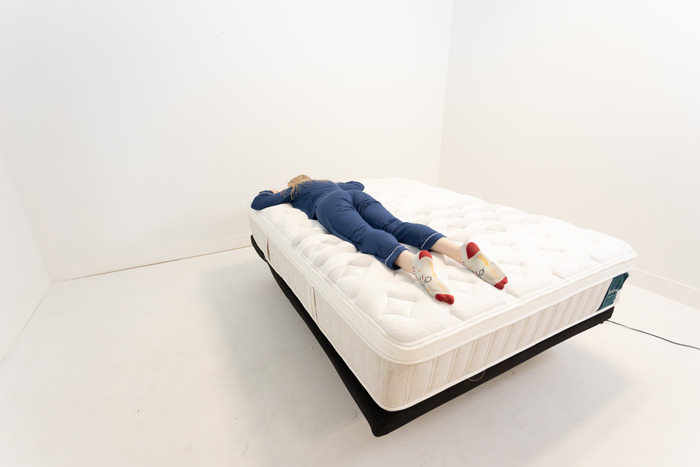 A woman lying on the Leesa Sapira Chill Hybrid mattress on her stomach.