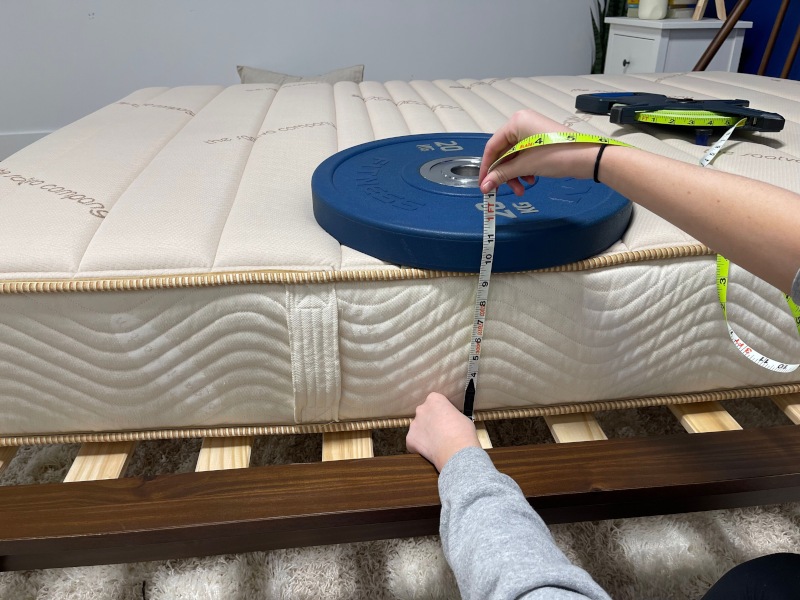 Our tester measures the compression of weight plates to assess edge support on a Saatva Youth Mattress
