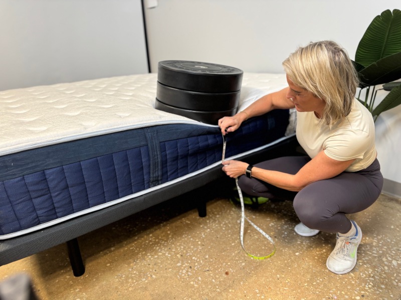 Our tester measuring weight plates on the edge of a Glacier Summit Hybrid Mattress