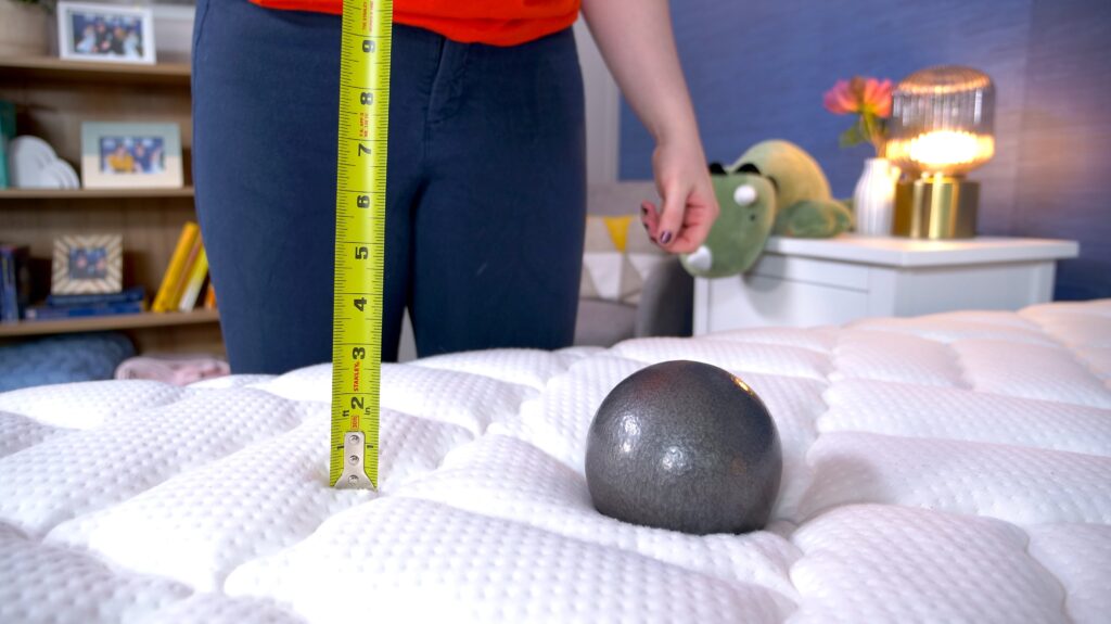 One of our testers using a tape measure and steel ball to measure motion transfer on the Brooklyn Bedding Titan Plus mattress.