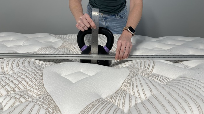 A kettlebell resting on the Nolah Evolution mattress, with a tester measuring its sinkage.
