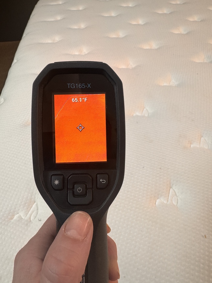 A closeup of someone using a thermal gun to read the Plank Firm's neutral temperature. The temperature reads 65.1 degrees.