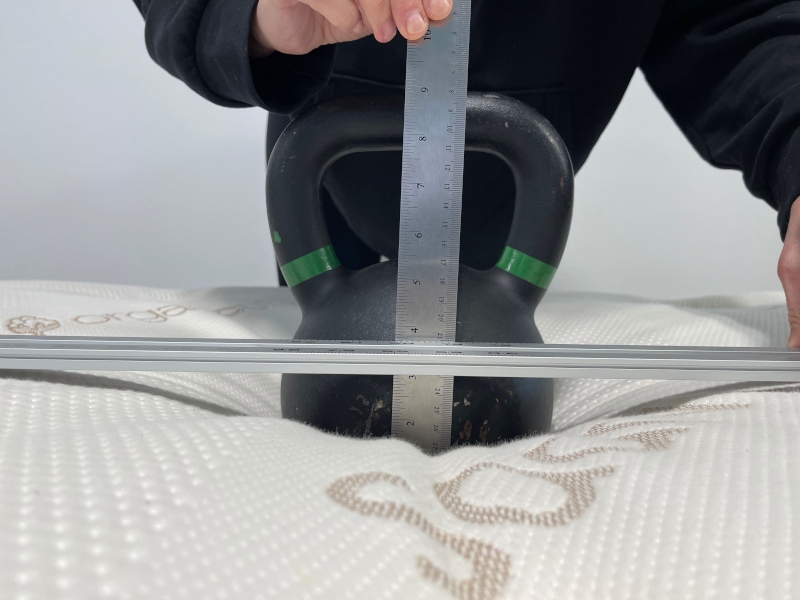 A person measures kettlebell deflection on the Saatva Latex Hybrid mattress.