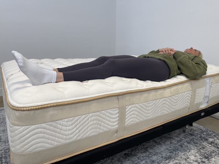 A woman lying on her back on the Saatva Rx.