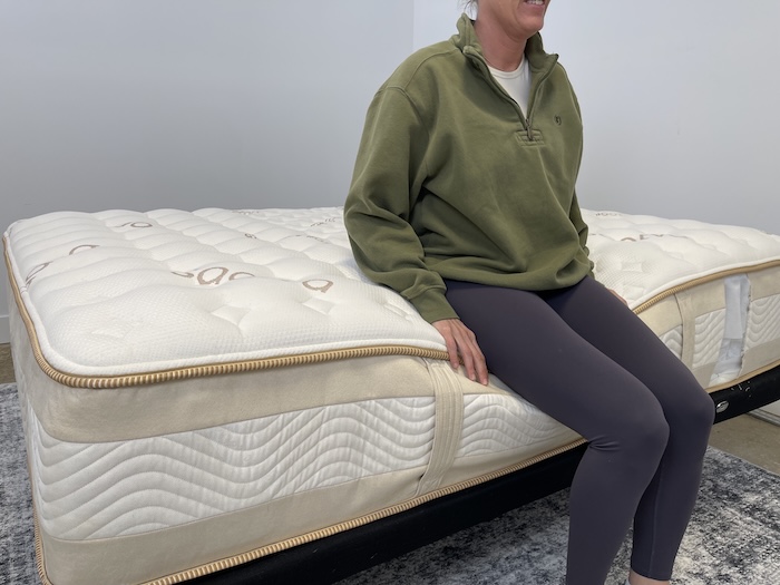 A woman sitting on the edge of the Saatva Rx to test out its edge support.