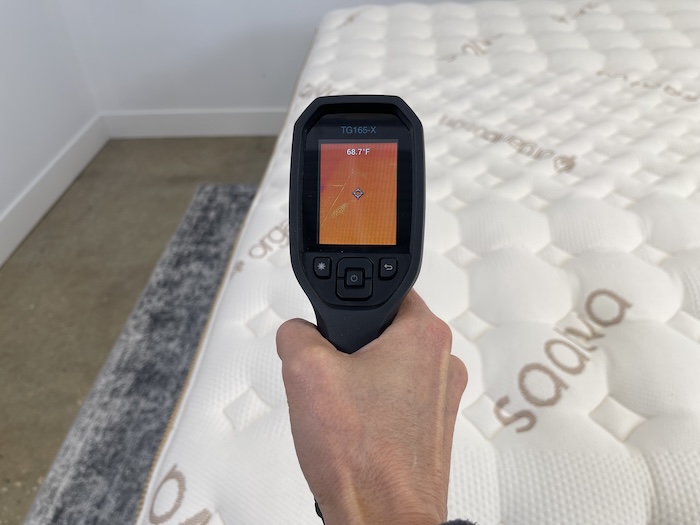 A closeup of someone using a thermal gun to take the neutral temperature of the Saatva Rx. The screen reads 68.7 degrees.