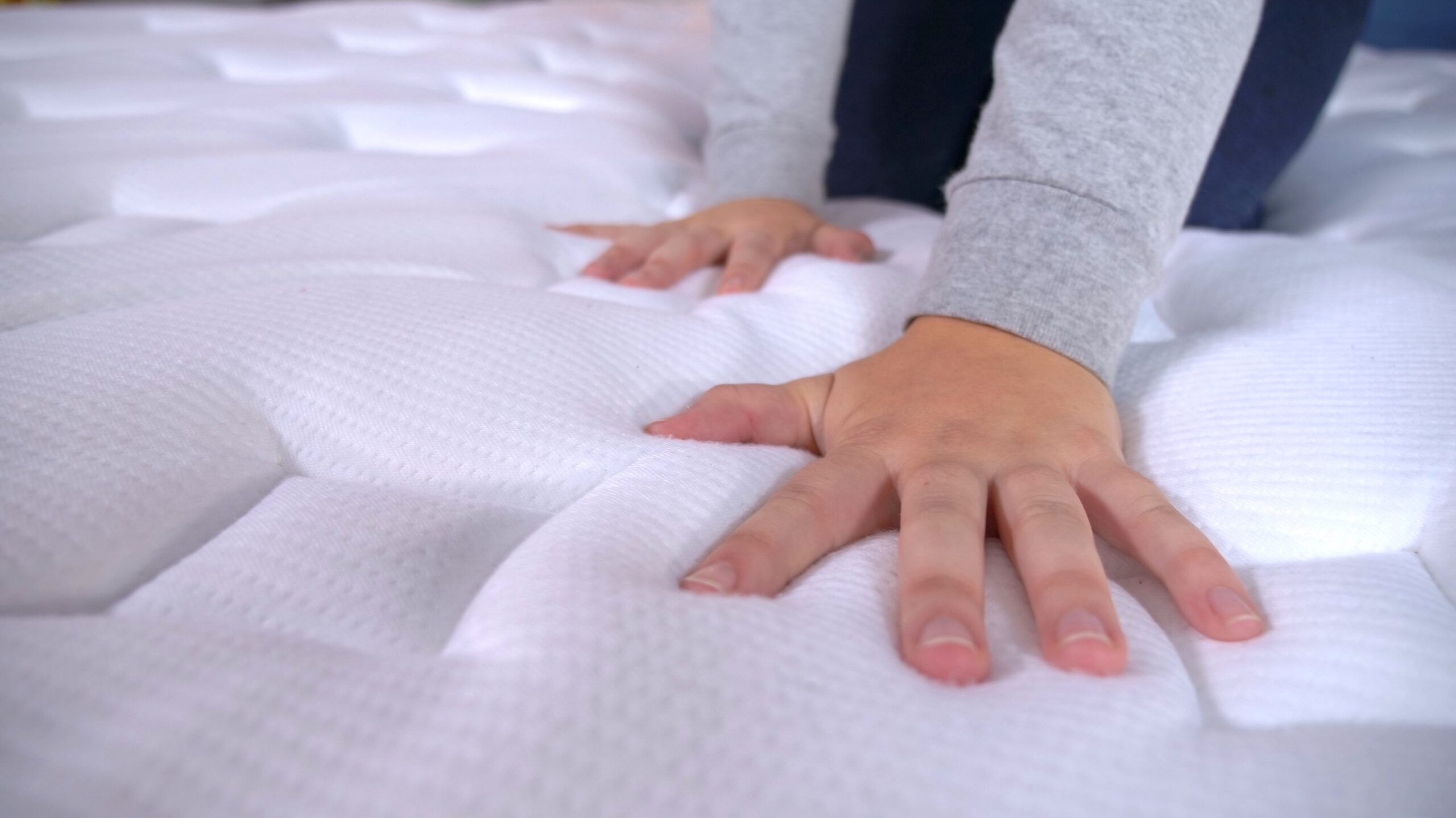 Two hands pushing down on mattress