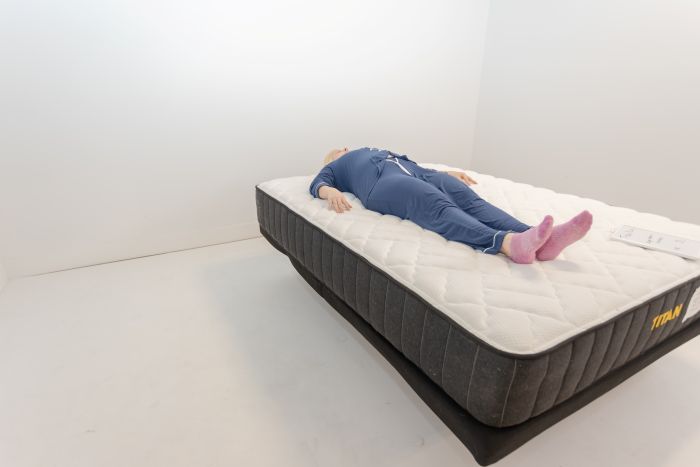 A woman lays on her back on the Titan Plus mattress