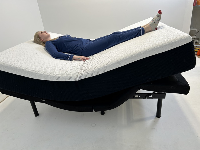 A woman lying on her back on the Nectar mattress while it's on an adjustable base.