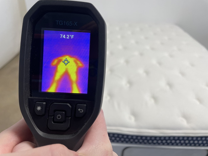 A closeup of someone using a thermal gun to measure the WinkBed's temperature after someone has rested on it for 5 minutes. The screen reads 74.2 degrees.