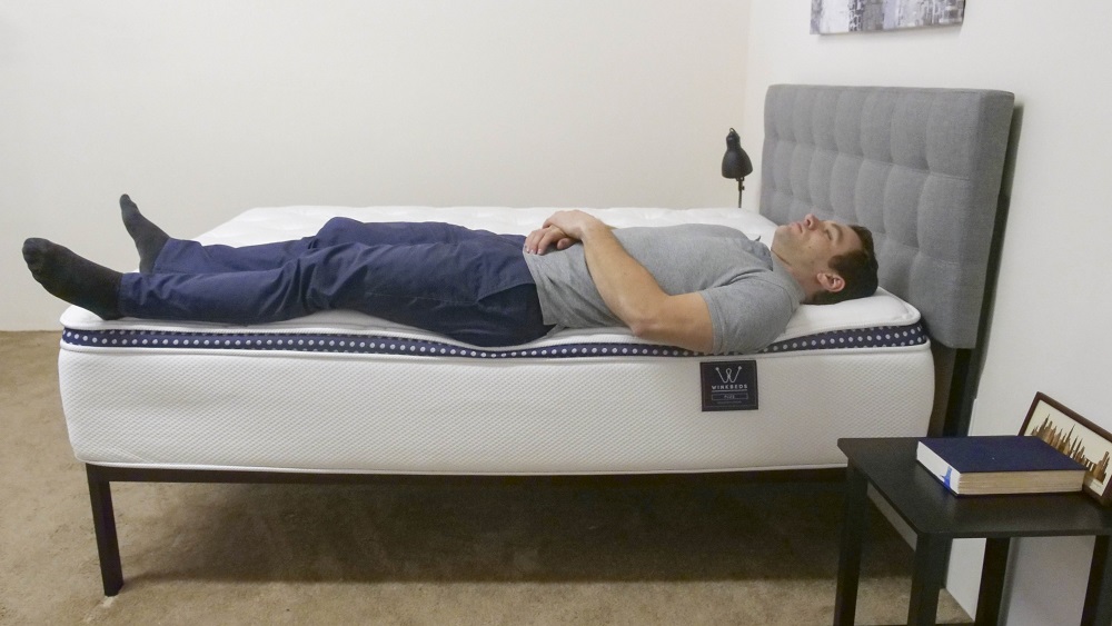 A man sleeping on his back near the edge of the WinkBed Plus.